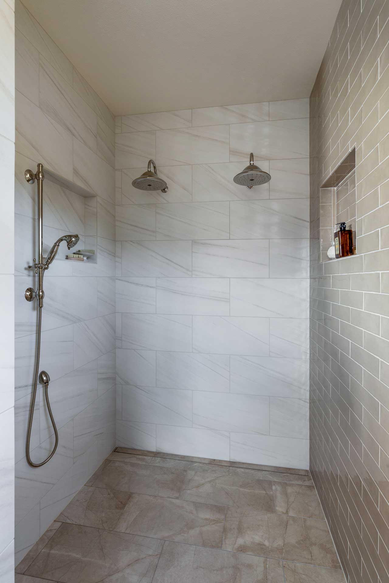 Modern walk-in shower with dual rainfall showerheads and subway tile design.