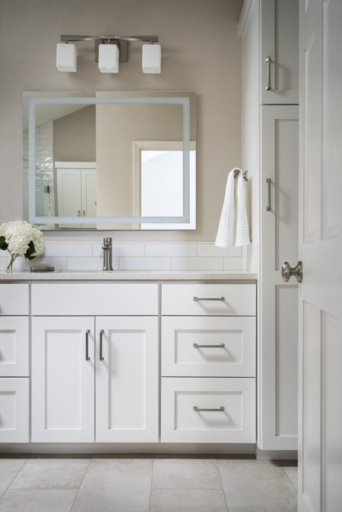 Modern white bathroom vanity with large mirror and decorative lights.