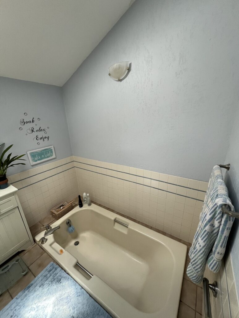Modern bathroom with a white bathtub, towel rack, and decorative wall quote.