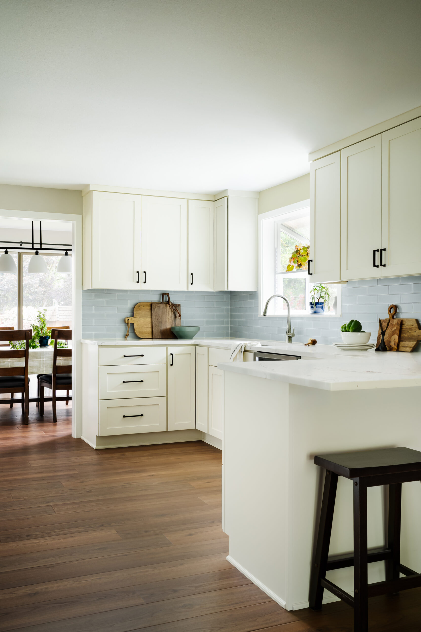 Bright, modern kitchen with white cabinets, marble countertops, and light wood flooring.