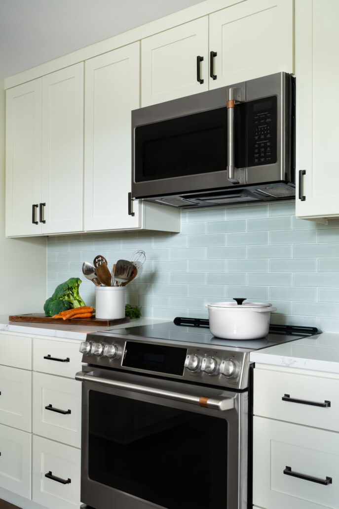 Modern kitchen with stainless steel appliances, white cabinets, and fresh vegetables on the counter.