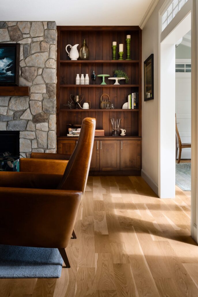 Cozy living room with leather chairs, stone fireplace, and wooden shelves displaying decorative items.