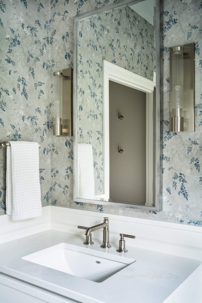Elegant bathroom vanity with floral wallpaper, sleek fixtures, and a large mirror reflecting natural light.