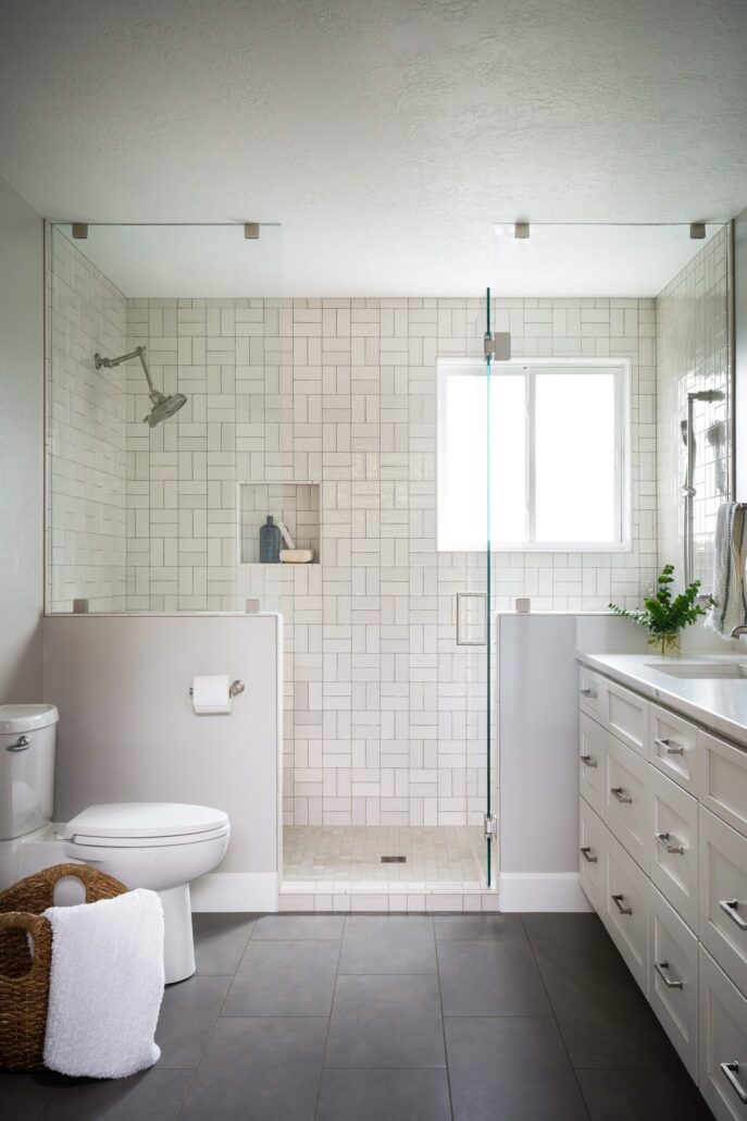 Modern bathroom with glass shower, white tiles, and sleek cabinetry. Bright, clean, and elegant design.