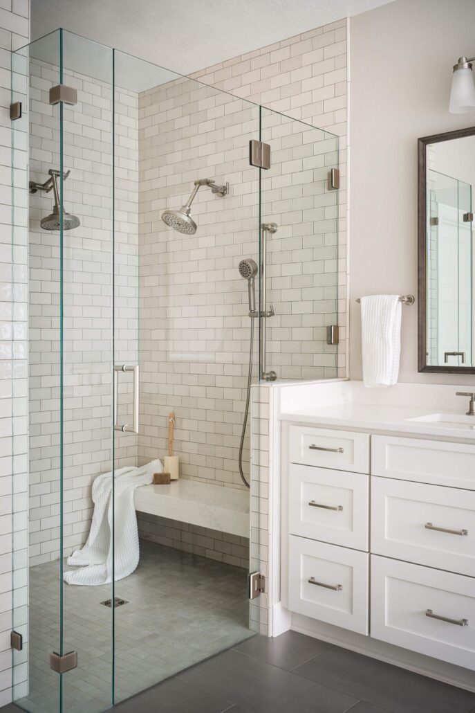 Modern bathroom with glass shower, white tiles, and sleek vanity. Minimalist design for a clean, spacious feel.