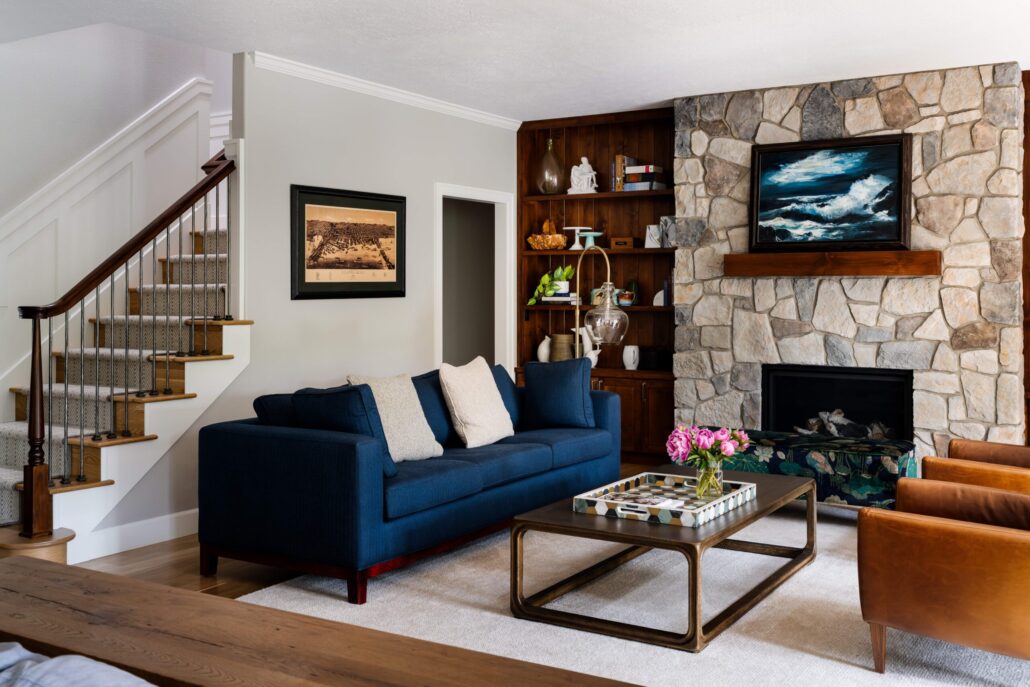 Stylish living room with blue sofa, stone fireplace, and modern decor. Cozy and elegant interior design.