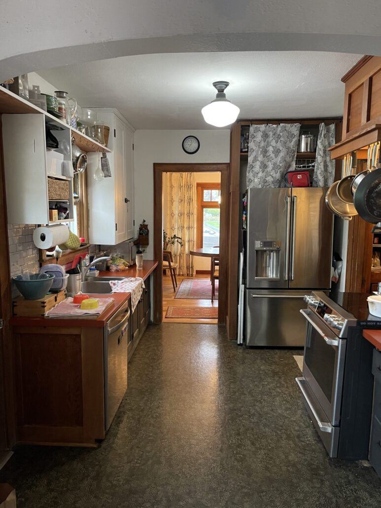 Cozy vintage kitchen with brown cabinets, stainless appliances, and view to dining room. Homey and inviting atmosphere.